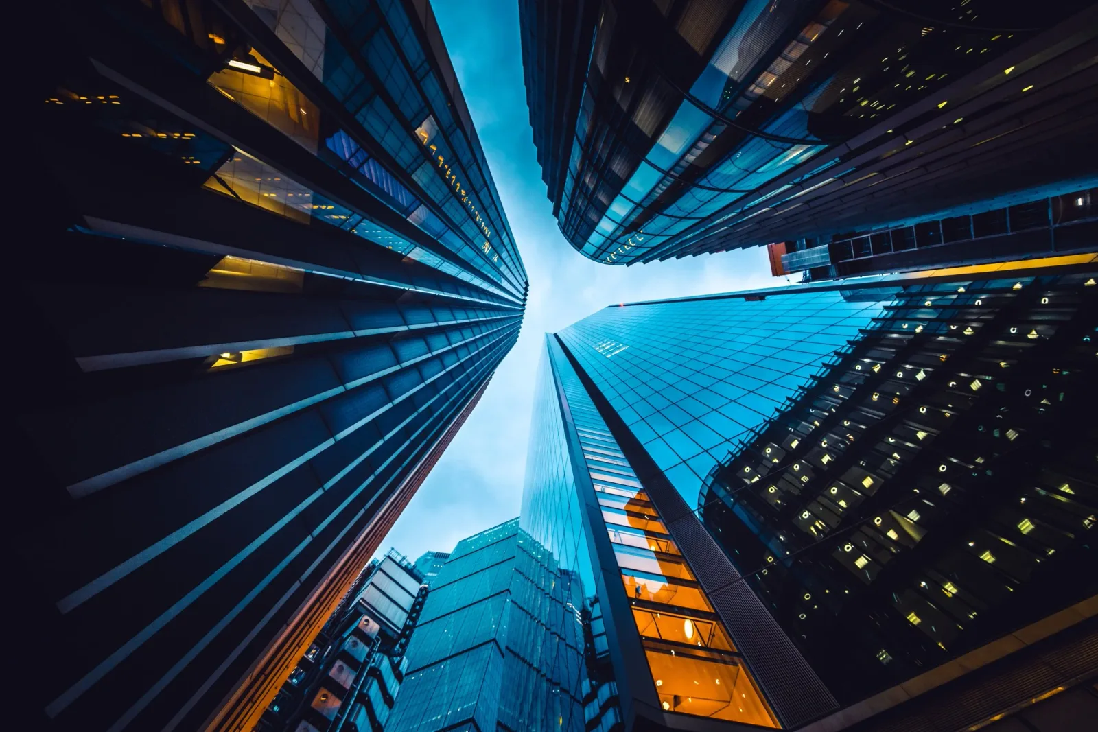 Looking up at skyscrapers with glass facades in a city.